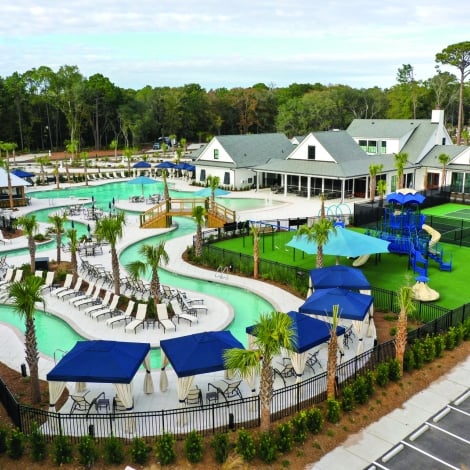 Pool with lounge chairs surrounding and pickleball courts on the right 